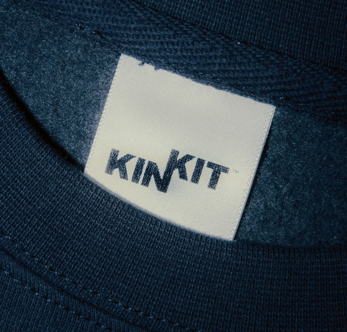 Close-up of a KIN KIT woven label on navy fabric